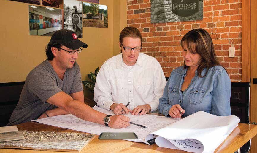 The Design Element team reviewing sign plans and material samples in the studio